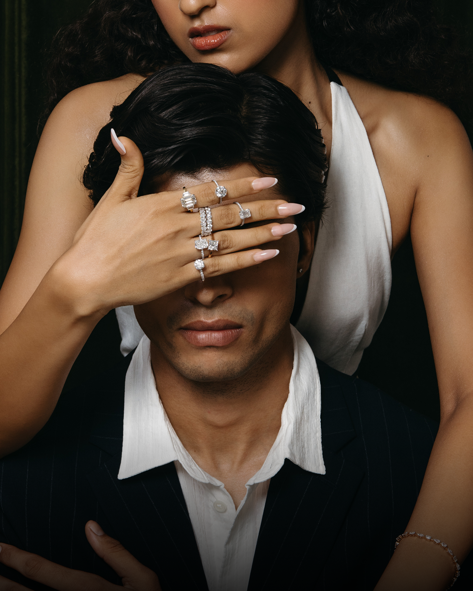 Woman covering man’s eyes, showing diamond rings
