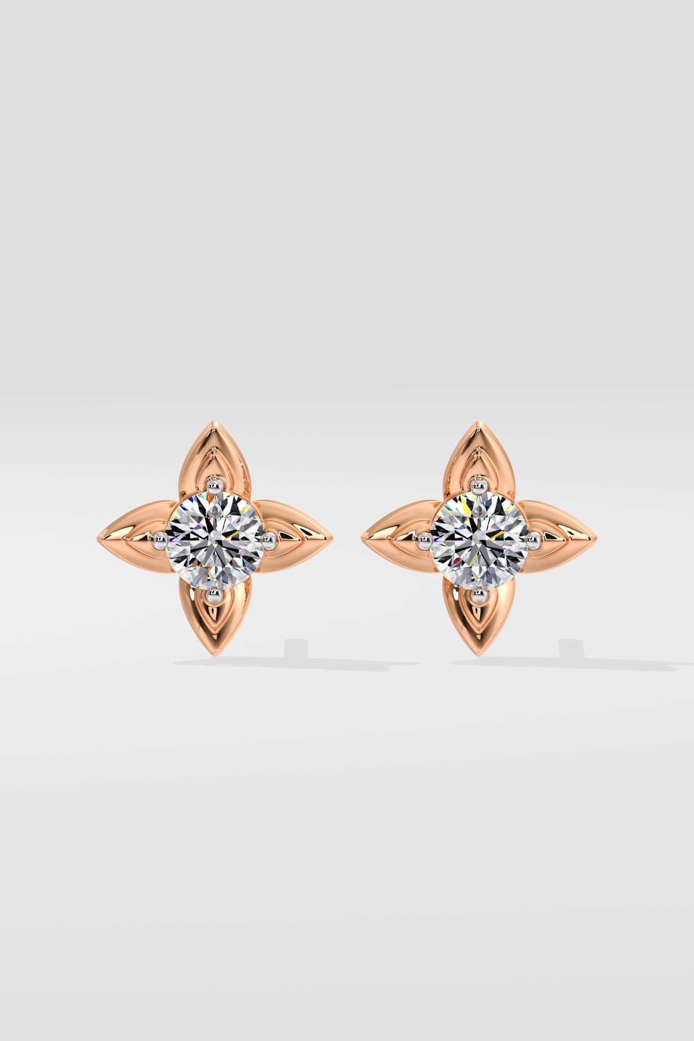 Pair of rose gold diamond earrings with clear gemstones on a light gray background