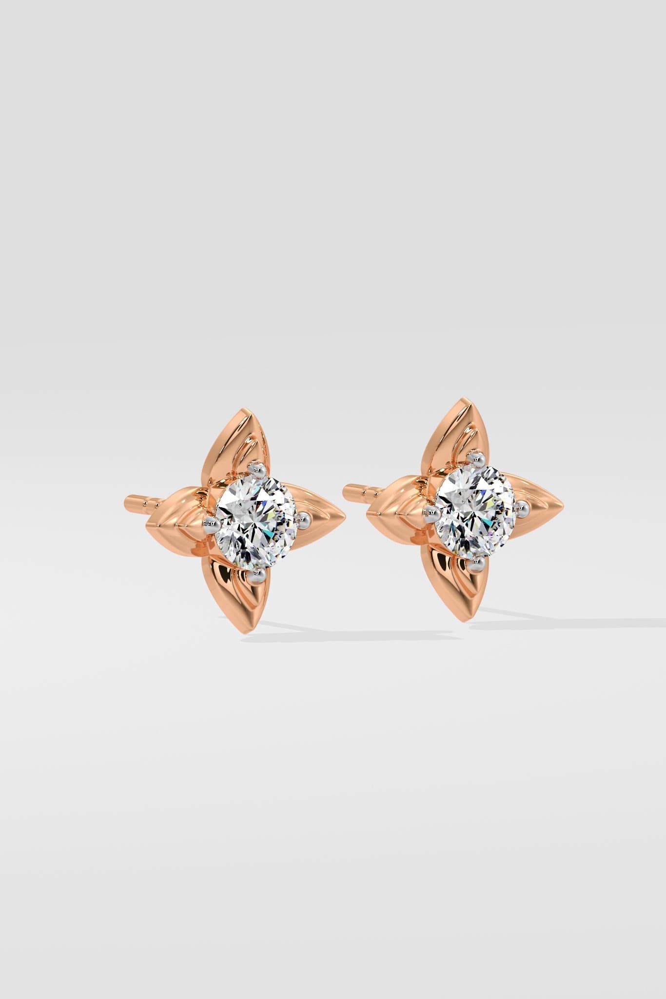 Rose gold diamond earrings with diamond-like stones on a light gray background