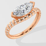 Rose gold diamond ring with a large diamond and smaller diamonds on the band against a light gray background